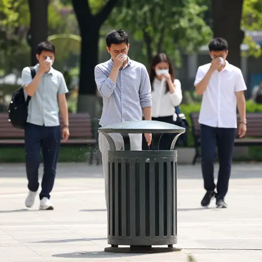 垃圾箱散发出令人作呕的恶臭，人们纷纷捂住鼻子。