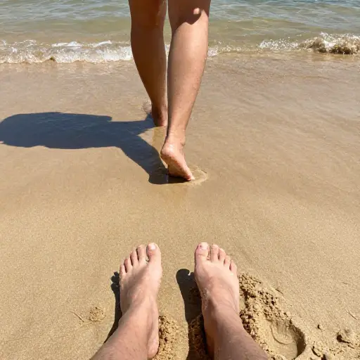 我正享受着温暖的沙子，把脚浸泡在冷水中，这时他的影子遮住了太阳。