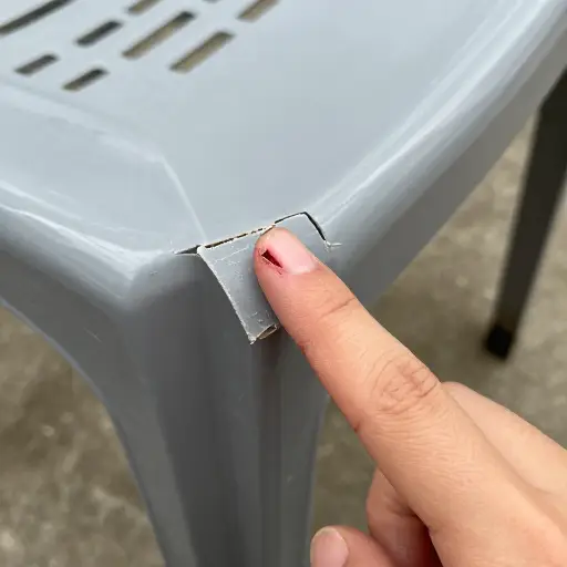 他的手指被塑料椅子破损的边缘割伤了。
